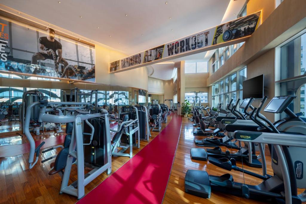a gym with a lot of treadmills and machines at Grand Millennium Al Wahda Hotel and Executive Apartments Abu Dhabi in Abu Dhabi