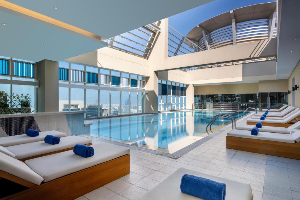 a large pool in a building with blue pillows at Grand Millennium Al Wahda Hotel and Executive Apartments Abu Dhabi in Abu Dhabi