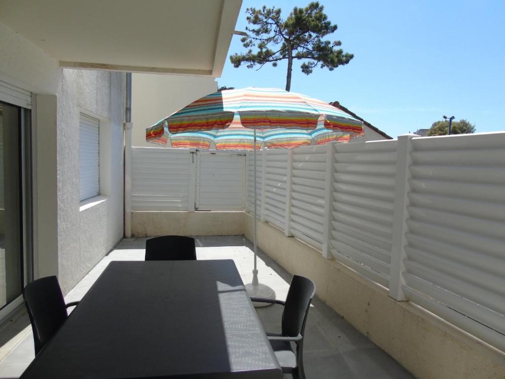 d'une terrasse avec une table et un parasol sur le balcon. dans l'établissement Les Genêts, à Saint-Jean-de-Monts