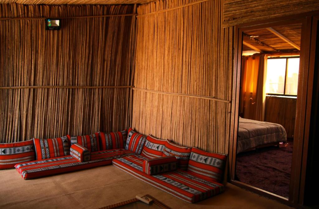 een kamer met 2 stoelen, een spiegel en een bed bij Wahiba Bedouin Rustic Camp in Muntarib