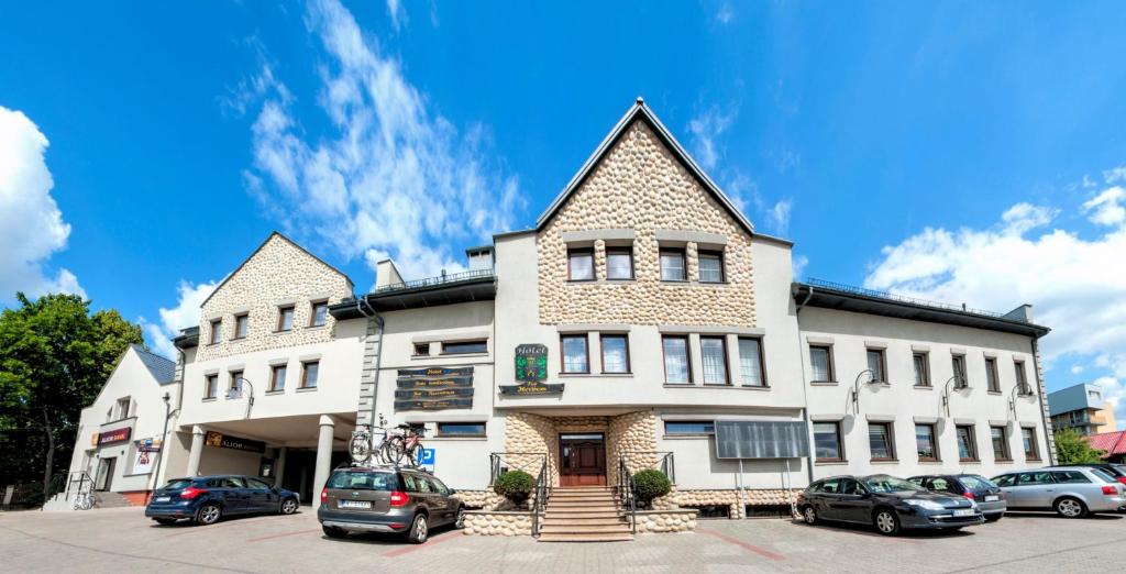 un gran edificio blanco con coches aparcados en un aparcamiento en Hotel POD HERBEM -POKOJE OZONOWANE, en Białystok