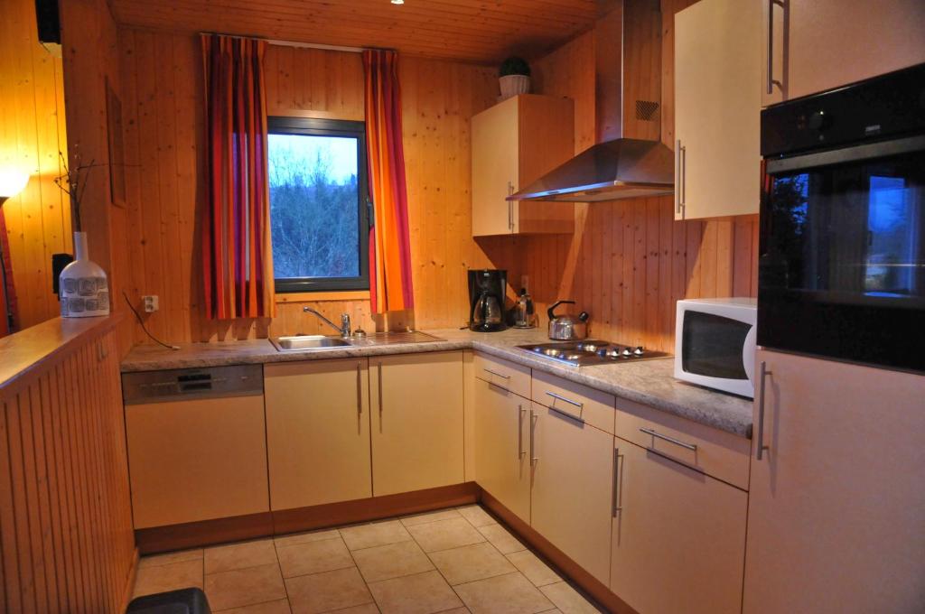 a kitchen with white cabinets and a microwave at Jardins de L'Ourthe 8 in Houffalize