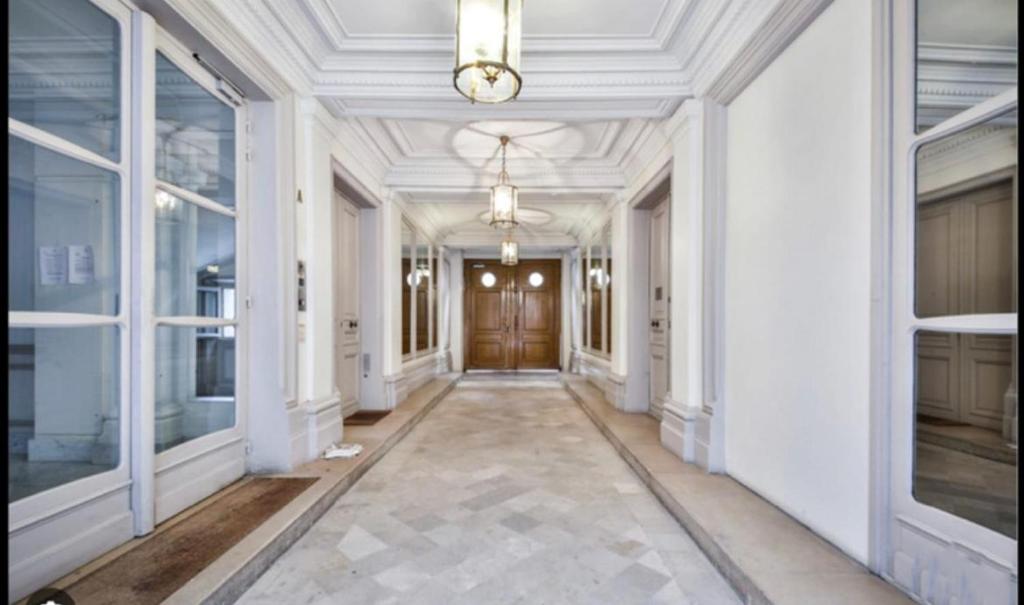 un couloir avec des murs blancs et un plafond avec une porte dans l'établissement L'avenue Montaigne, à Paris