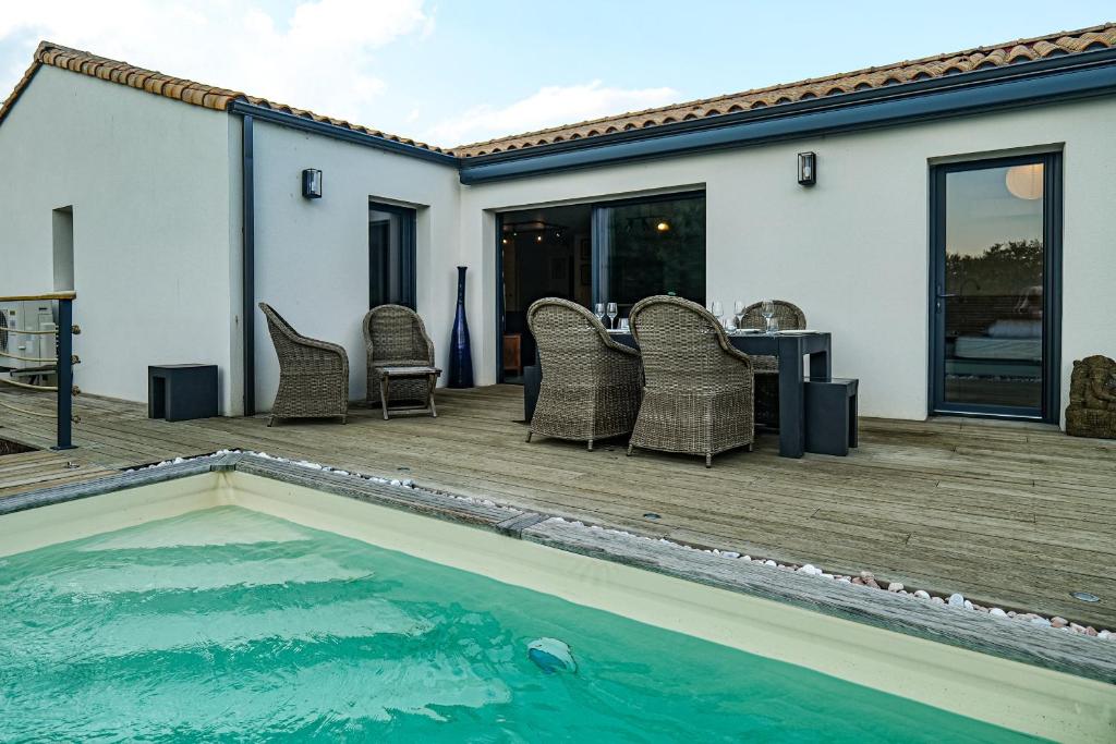 une terrasse avec une piscine, des chaises et une table dans l'établissement Jolie maison récente avec jardin et piscine Les Sables - 8 personnes, à Les Sables-dʼOlonne