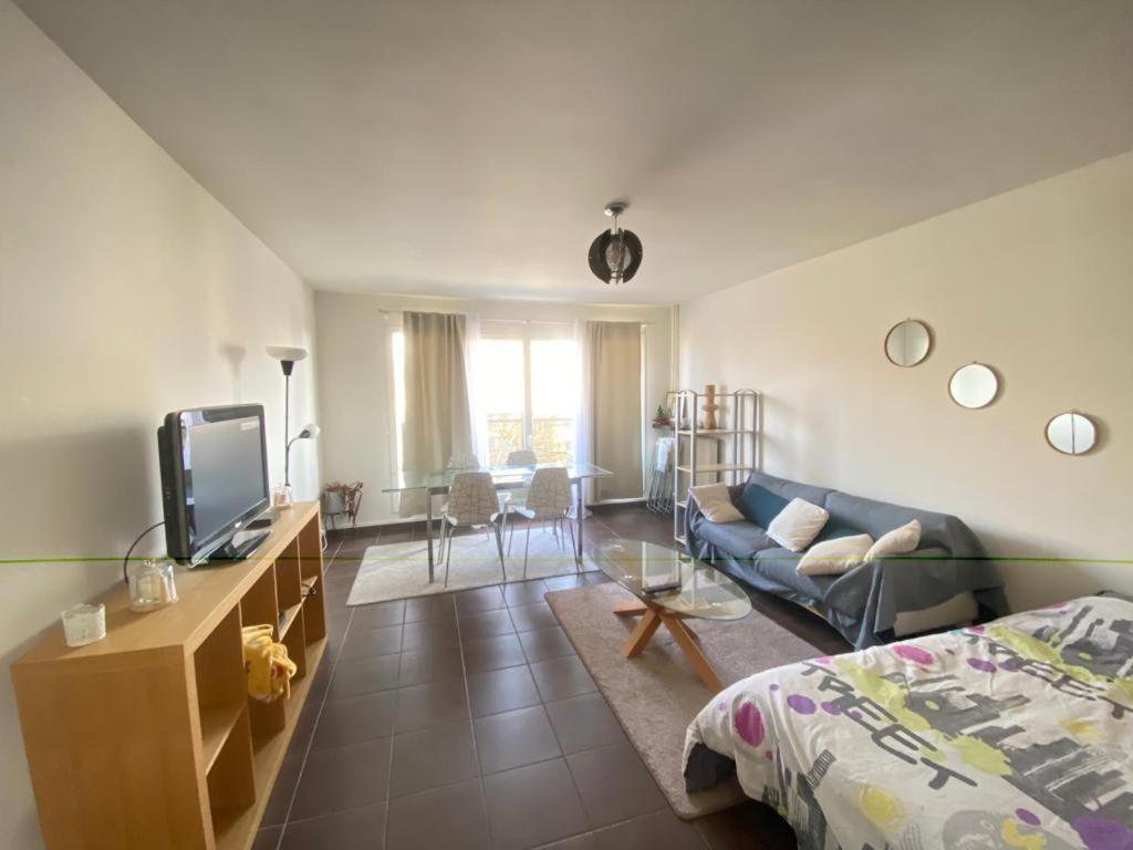 un salon avec un canapé et une télévision dans l'établissement Appartement familial proche de Paris, au Bourget