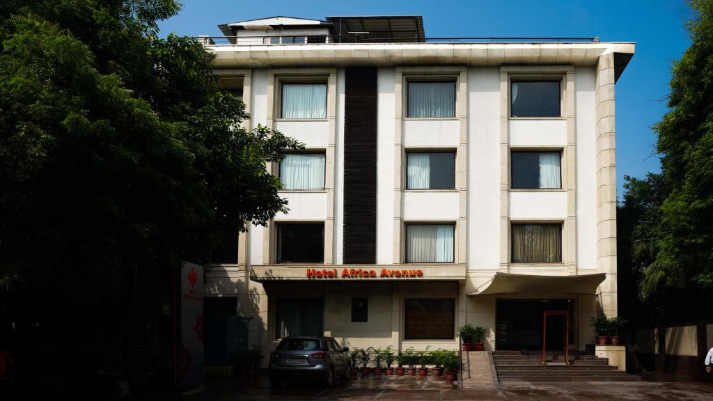 Un edificio blanco con un cartel en él. en Hotel Africa Avenue - Greater Kailash 1, en Nueva Delhi