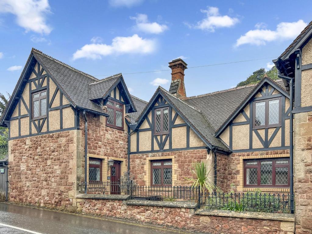 an old brick house with a black roof at One Grooms Cottage, Dunster in Dunster