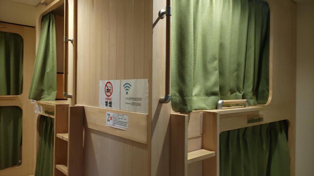 a bathroom with green shower curtains and a mirror at 日本ワインバックパッカーズ in Tokyo