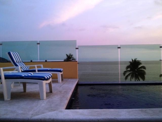 Duas cadeiras sentadas ao lado de uma piscina numa varanda em Andressa Mia Apartments em Manzanillo