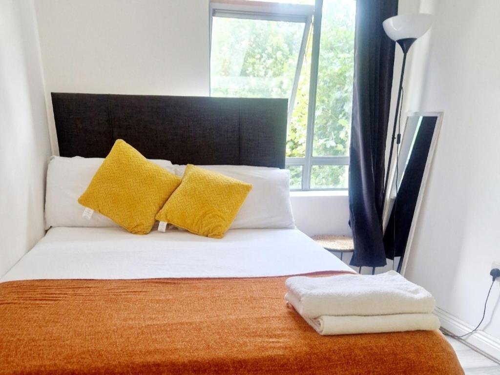 ein Schlafzimmer mit einem Bett mit gelben Kissen und einem Fenster in der Unterkunft Contemporary 2 bedroom apartment in limerick city in Limerick