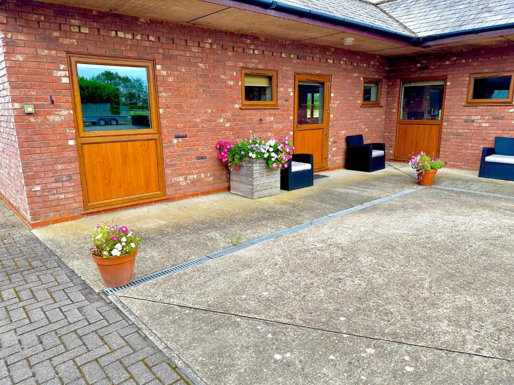 a brick building with two pots of flowers on a patio at Bluebell Cottage - Cedar Park in Grimsby