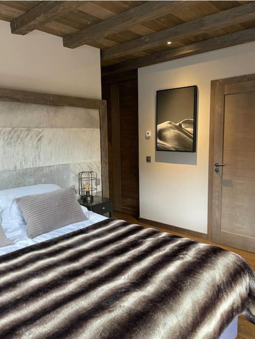 - une chambre avec un grand lit et une couverture rayée dans l'établissement Chalet Purdey - Sleeps 10 with Hot Tub, à Montriond