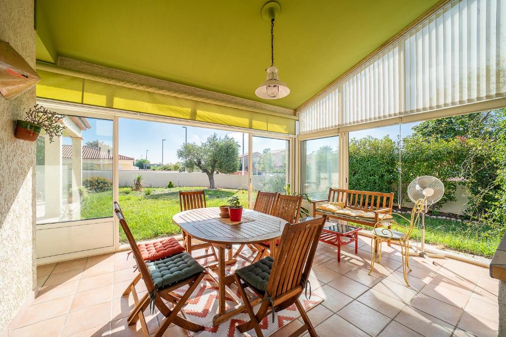 une véranda avec une table et des chaises dans l'établissement La Villa Noémie - À 10mn de Perpignan, à Saleilles