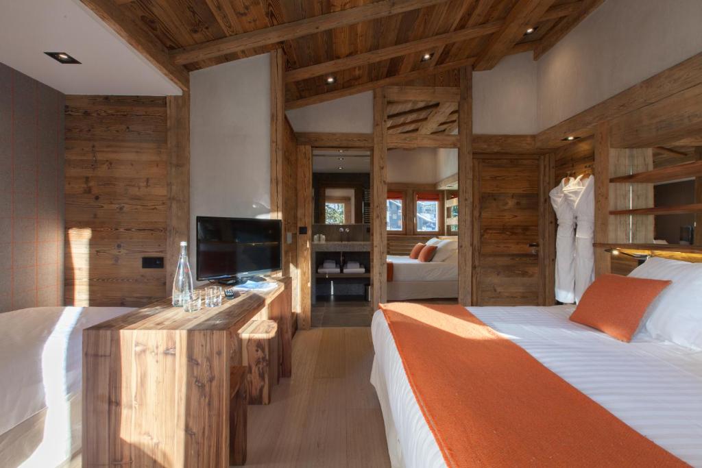a bedroom with two beds and a television in it at Au Coin Du Feu in Megève