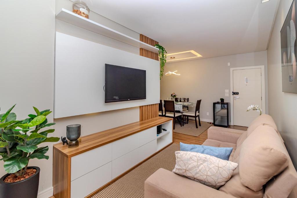 Una sala de estar con un sofá y un televisor. en A 30 passos da praia! Localização top em BC - Perto de tudo!, en Balneário Camboriú