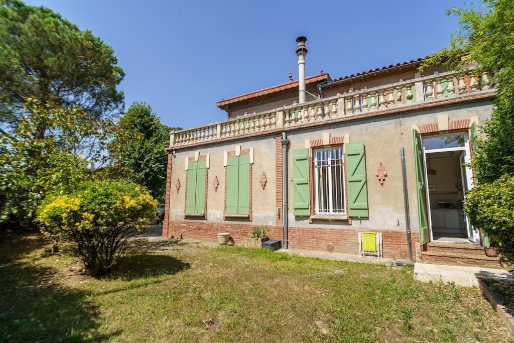 une vieille maison avec des volets verts et une cour dans l'établissement Studio Jardin à la Villa Odette, à Toulouse