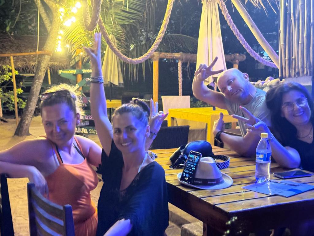 a group of people sitting at a table with their hands in the air at Frangipani Beach Villa in Tangalle