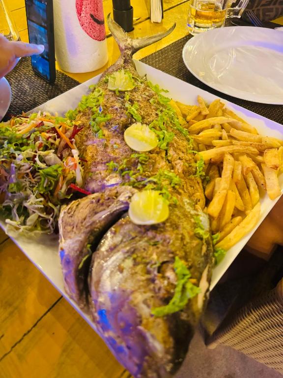 a plate of food with a fish and french fries at Frangipani Beach Villa in Tangalle