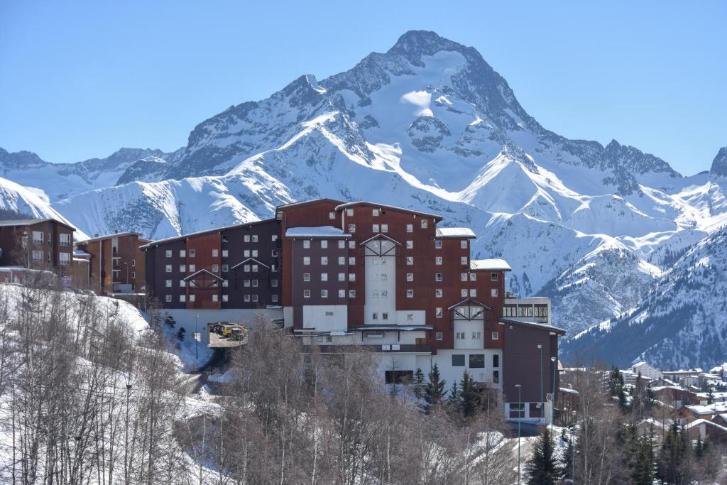 un bâtiment sur une colline avec une montagne en arrière-plan dans l'établissement Villages Clubs du Soleil - LES 2 ALPES, à Les Deux Alpes