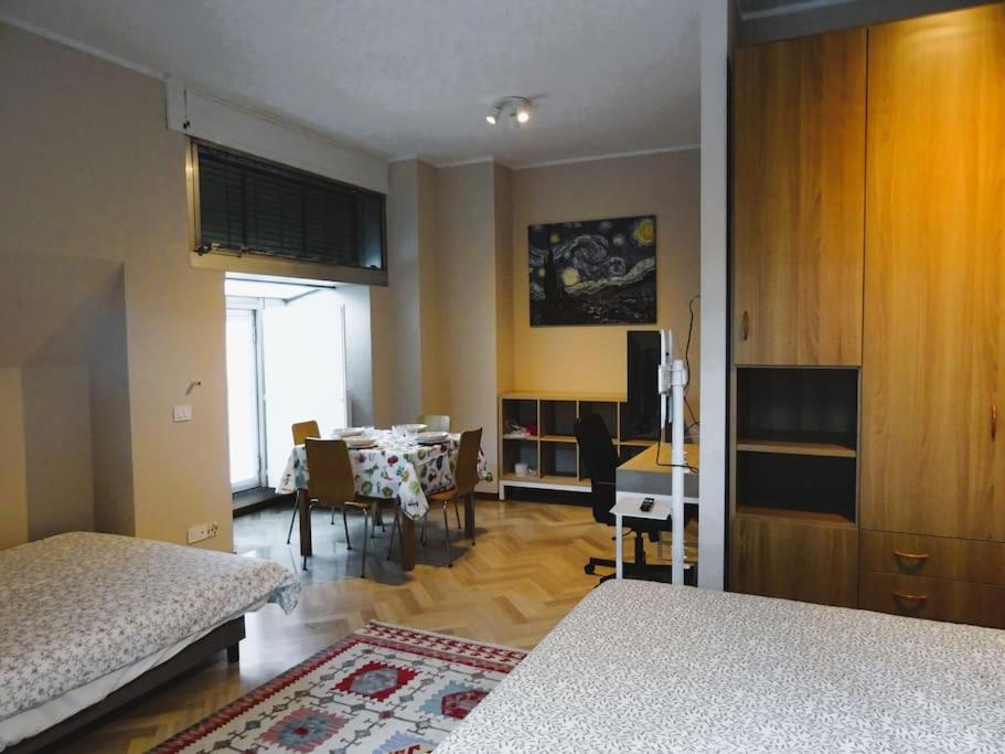 a room with a bedroom with a table and a dining room at Ampio monolocale vicino al lungolago di Lecco in Lecco