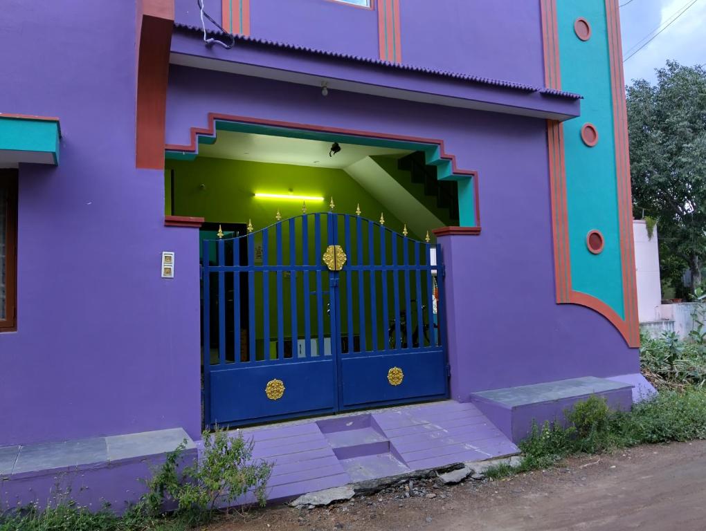 Un edificio morado con una puerta azul al frente. en Arunachala Home Stay, en Tiruvannāmalai
