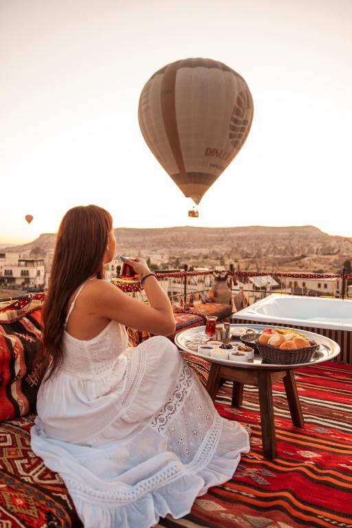 a woman sitting on a couch watching a hot air balloon at Tantan Cappadocia House in Avcılar