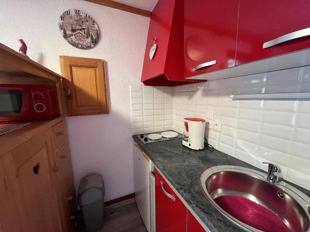 - une petite cuisine avec un évier et des placards rouges dans l'établissement Studio cosy avec balcon, proche télécabine, 4 pers, cuisine équipée, TV et Multispass inclus - FR-1-198-128, à Châtel