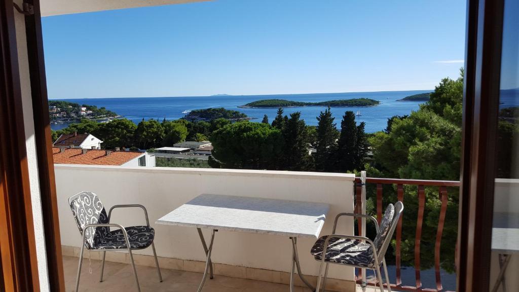 een tafel en stoelen op een balkon met uitzicht op de oceaan bij Apartments and Rooms Rogosic in Hvar