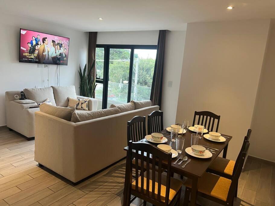 a living room with a couch and a table with chairs at Apartamento entero de 3 habitaciones con camas Queen en zona 10 in Guatemala