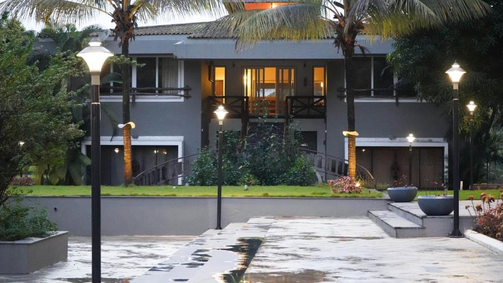 a house with palm trees in front of it at Golden Fields Resort in Mulshi