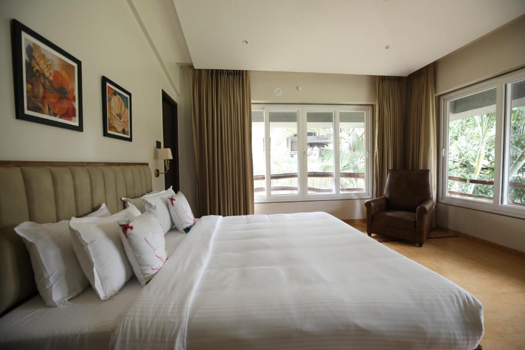 a bedroom with a large bed with white pillows and a chair at Golden Fields Resort in Mulshi