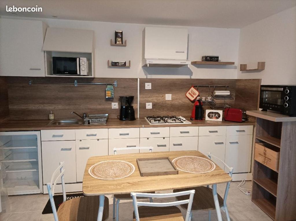 Il comprend une cuisine avec une table en bois et des placards blancs. dans l'établissement Chez Sabine La Campagne, à Narbonne