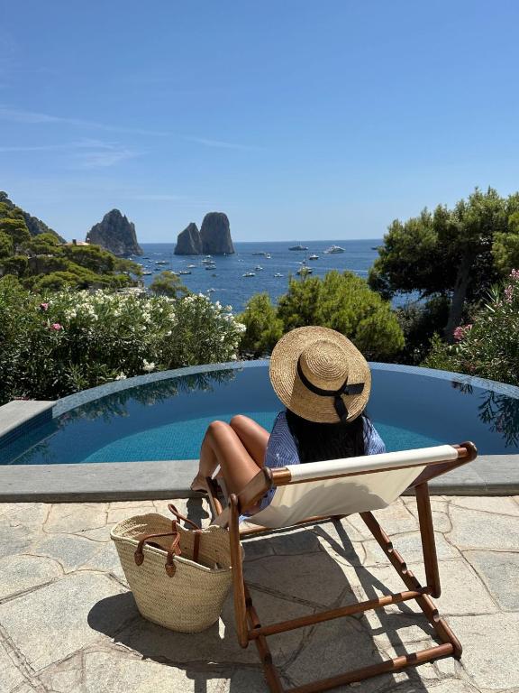 a woman sitting in a beach chair with a hat at Villa Roccia Di Mare in Capri