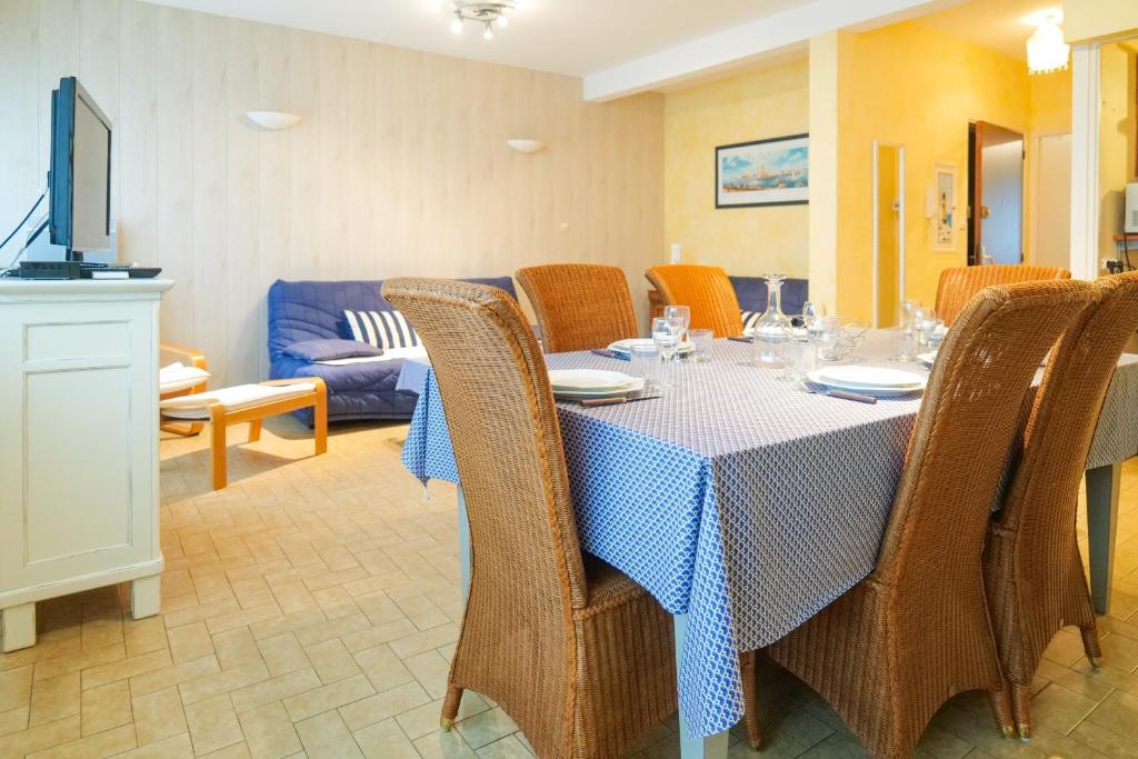 a dining room with a table and chairs and a couch at Appartement proche de la plage de Tanchet, quartier des Présidents Les Sables - 6 personnes in La Rudelière
