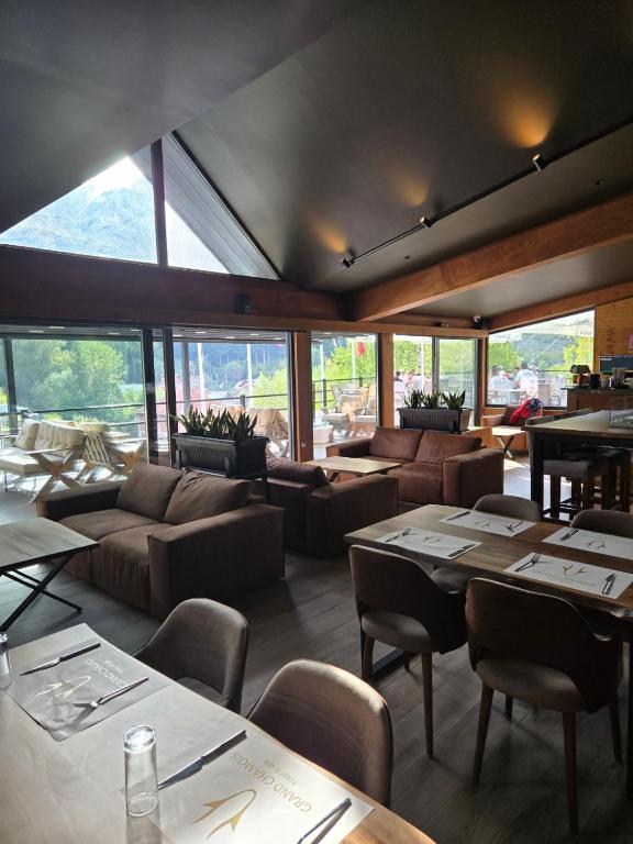 a restaurant with tables and couches and chairs and windows at Grand Chamois Hotel & Spa in Mavrovo