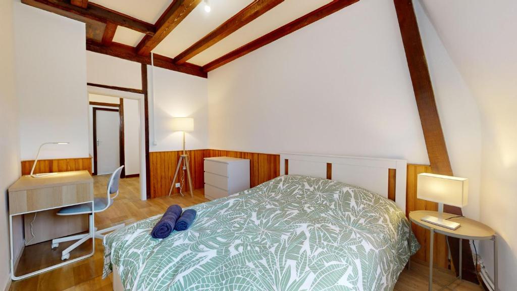 une chambre avec un lit dans une pièce avec des plafonds en bois dans l'établissement Le Carré Mulhousien, à Mulhouse