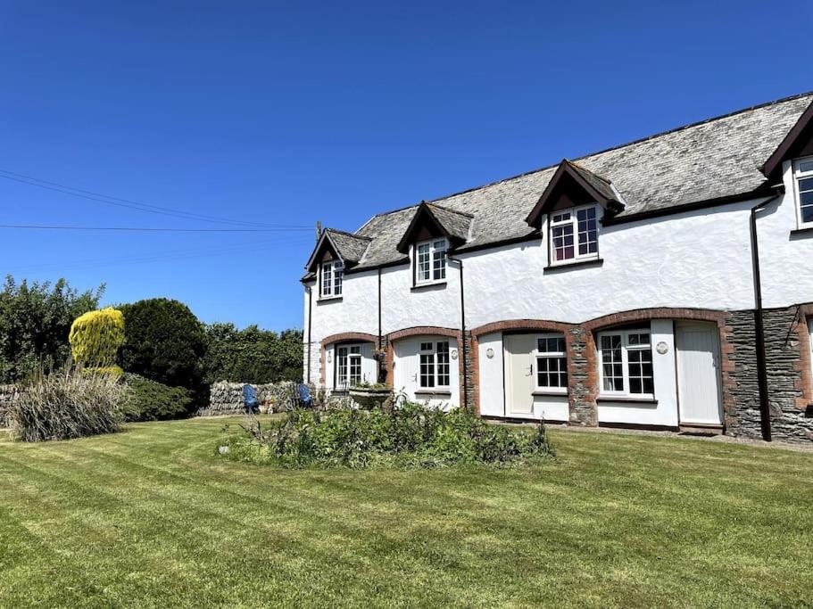 a large white house with a large yard at Marigold Cottage in West Down