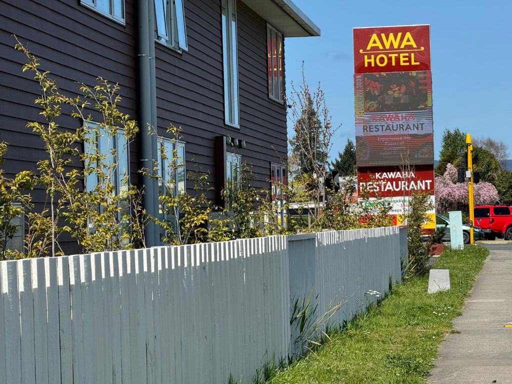una casa con una recinzione bianca e un cartello di AWA Hotel a Rotorua