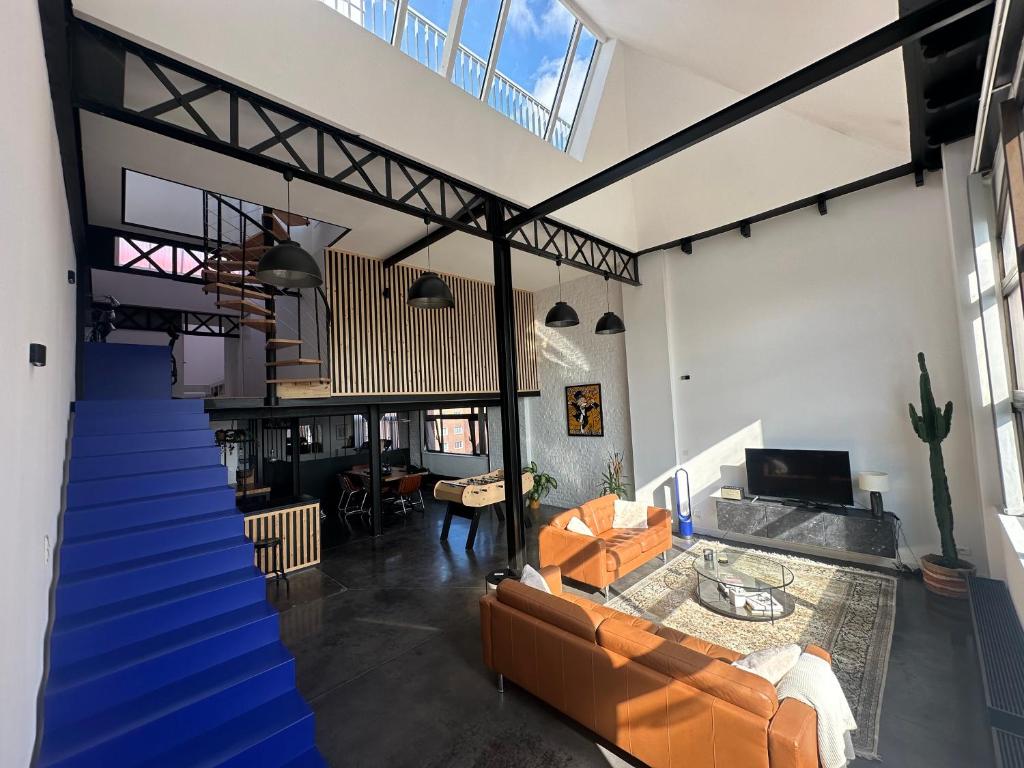 salon na otwartym planie ze schodami i pomarańczowymi meblami w obiekcie Loft duplex and rooftop w mieście Roubaix