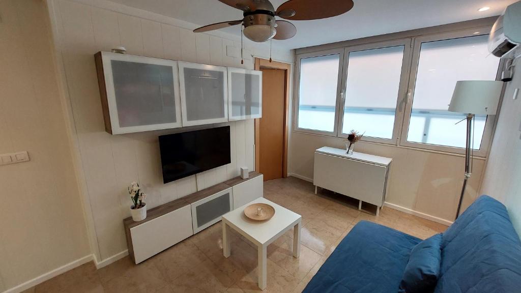 a living room with a blue couch and a tv at Playa, relax y parking público cerca - Ideal parejas in Cullera
