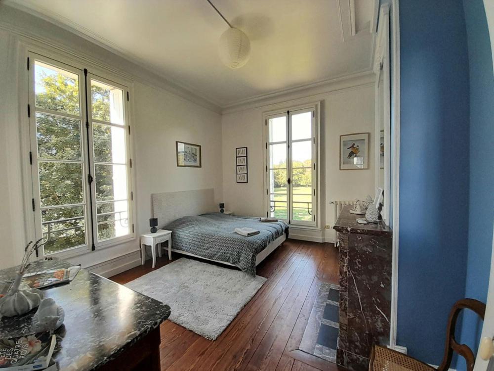 a living room with a bed and two windows at Aile Château La Chapelle du Bois des Faulx in La Chapelle-du-Bois-des-Faulx