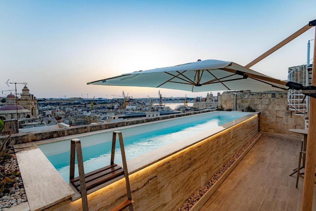 a swimming pool with an umbrella on top of a building at Authentic Maltese Boutique Holiday Home with Rooftop Pool - Moon Townhouse in Cospicua