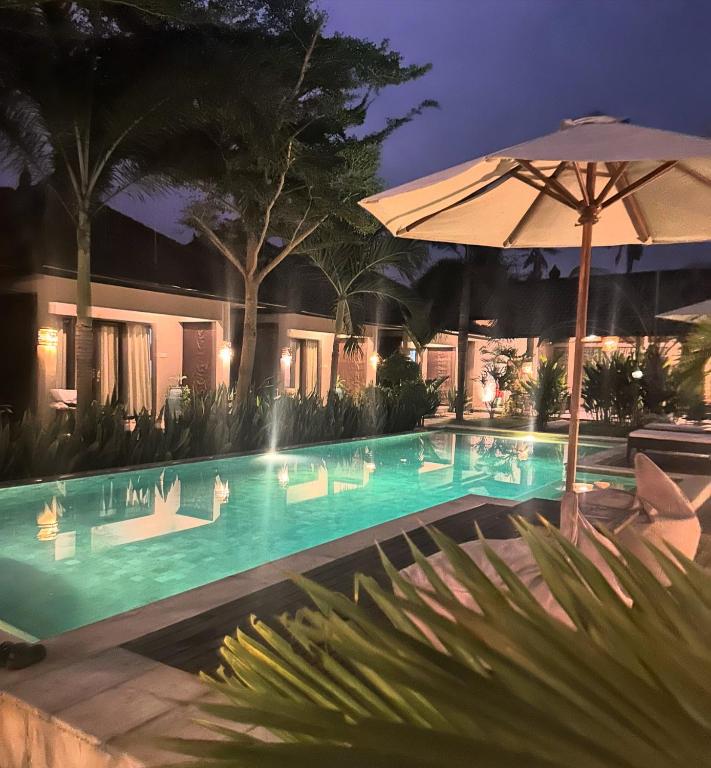 a swimming pool at night with an umbrella at Kaien Villas Gili Air in Gili Islands