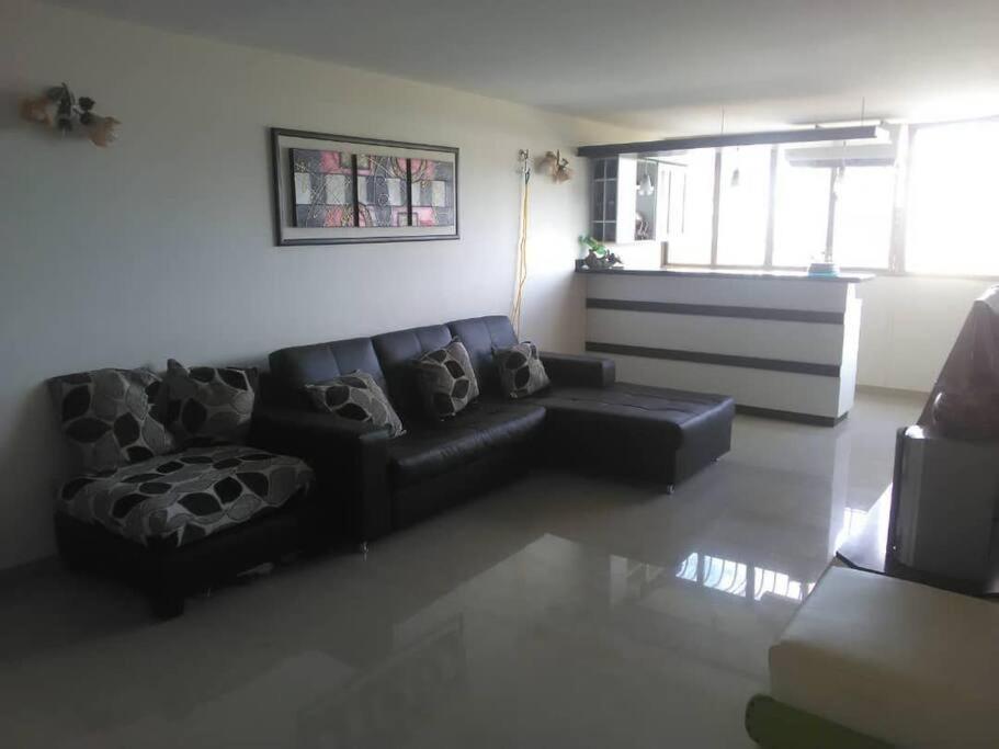 Una sala de estar con un sofá negro y una mesa. en ideal para vacaciones o trabajo, en Cumaná