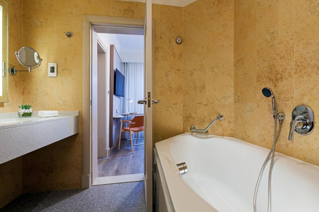 a bathroom with a tub and a sink at Malta Marriott Resort & Spa in St. Julianʼs