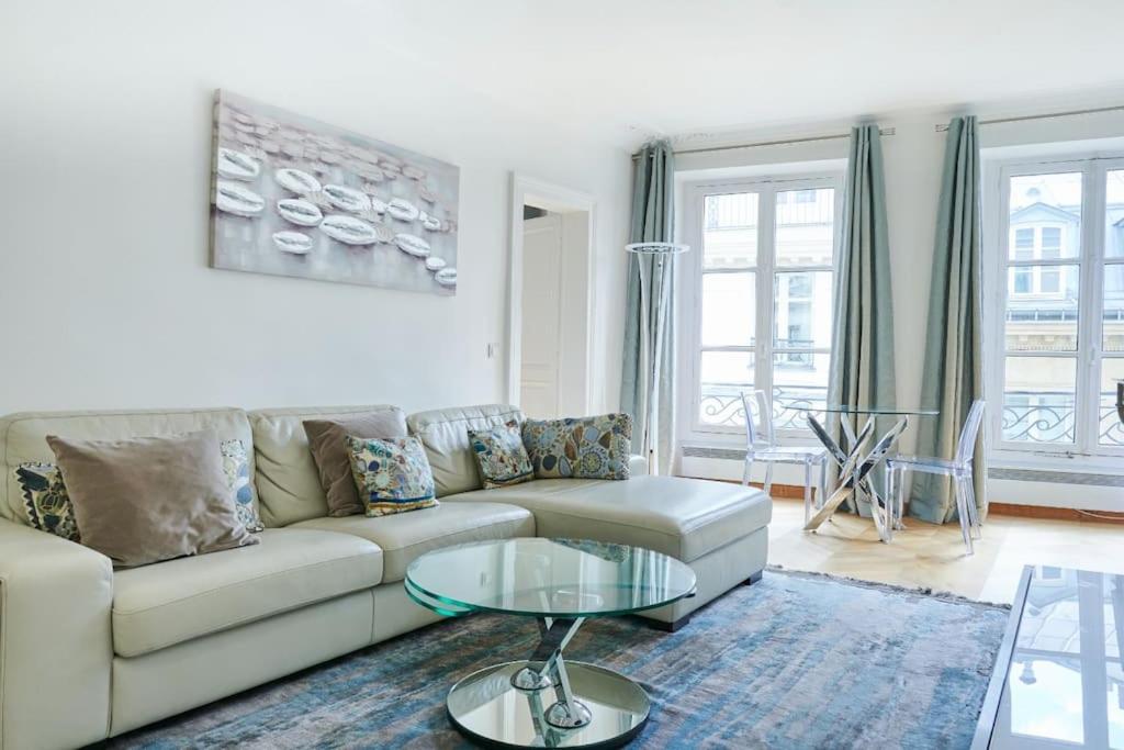 un salon avec un canapé et une table en verre dans l'établissement Appartement type F2 rénové- Quartier Elysée, à Paris