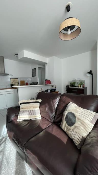 - un canapé en cuir brun dans le salon dans l'établissement Appartement de L, à Saint-André-de-Cubzac