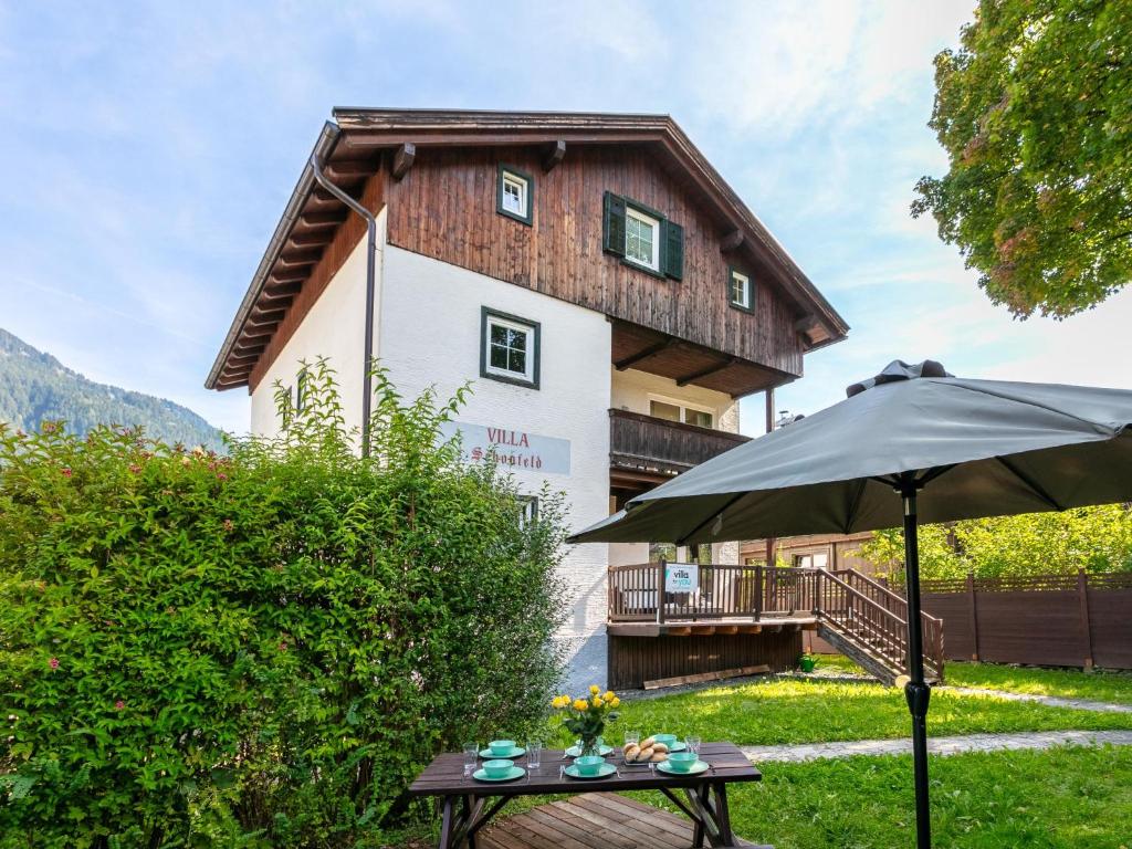 a house with a table and an umbrella in front of it at Schönfeld I in Kitzbühel