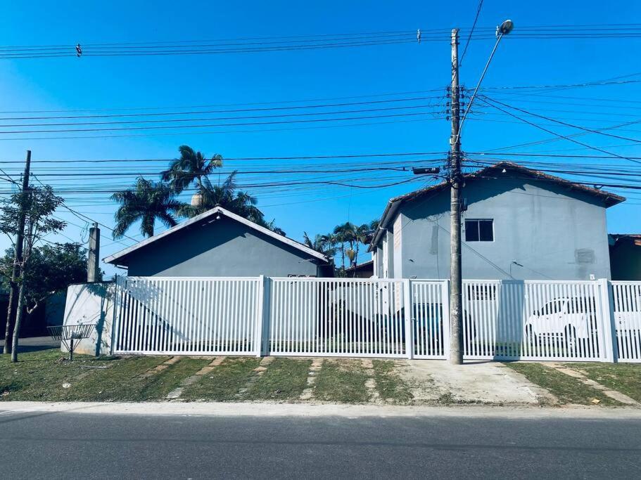 a white fence in front of a white house at Apartamento Itaguá in Ubatuba