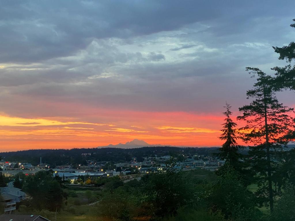 a sunset over a city with a mountain in the background at Cabin - Hot tub - Fire pit - View - Getaway! in Oak Harbor